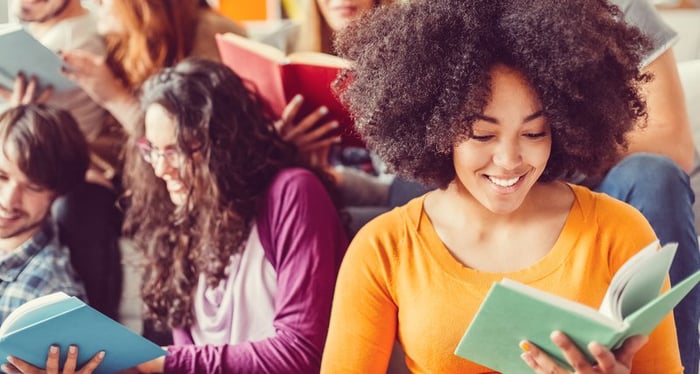 Group of students reading textbook in classroom