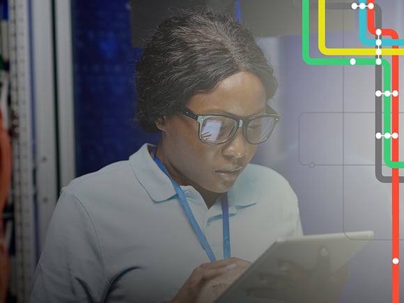 Woman uses a tablet in a room with various wires, cables, and technical equipment