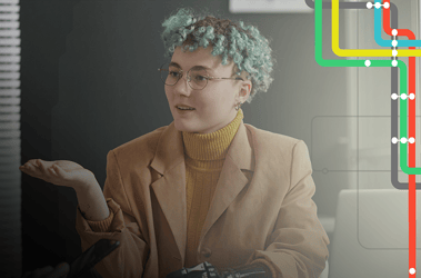 Young professional woman speaks to coworker at desk
