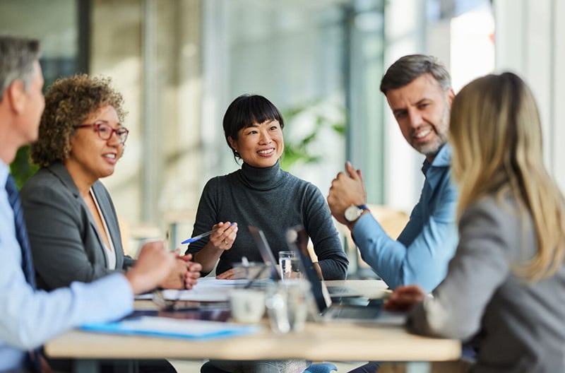Group of office workers sit at a table for a business meeting