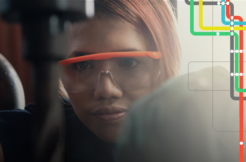 Young adult woman wearing safety glasses operates machinery 