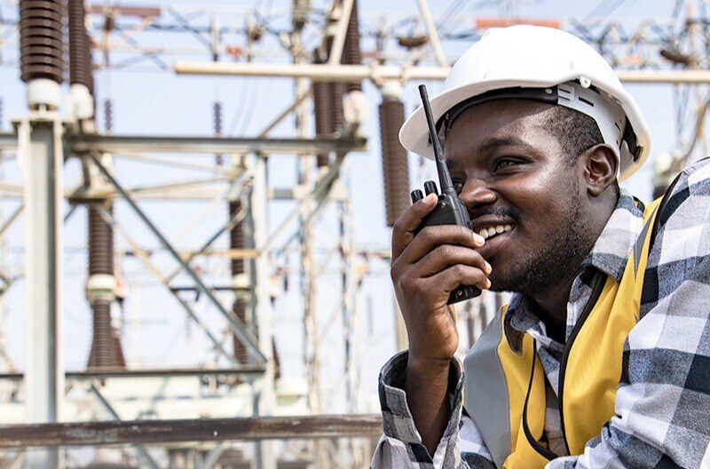 Young worker wearing hard hat uses walkie-talkie on job site