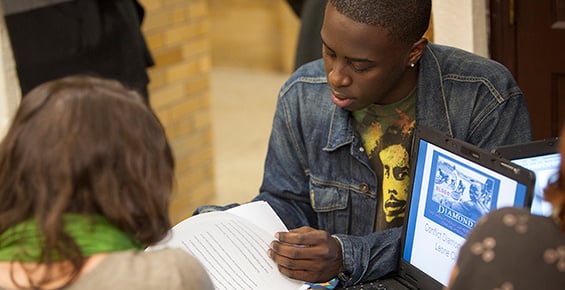 Image of college student reading in a crowded room.
