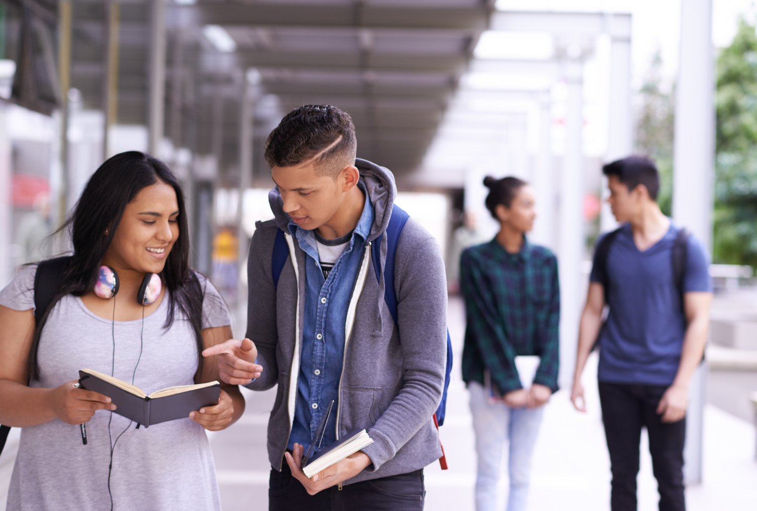 Two young people walking and talking while looking at a book