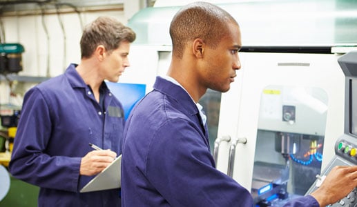 Two men analyzing equipment while one writes down data