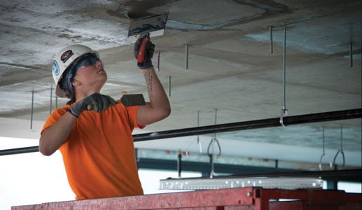 Young woman applying cement on ceiling