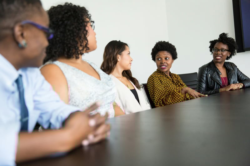 A group of people sitting at a conference table talking.