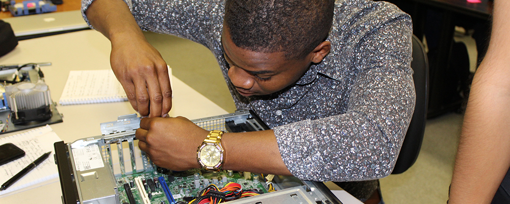 Photo of a training program participant working on computer repairs.